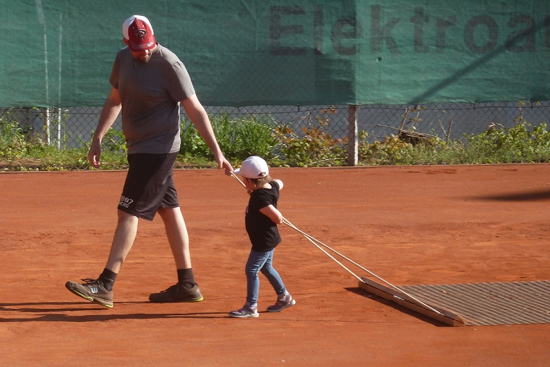 Vater und Kind pflegen den Tennisplatz