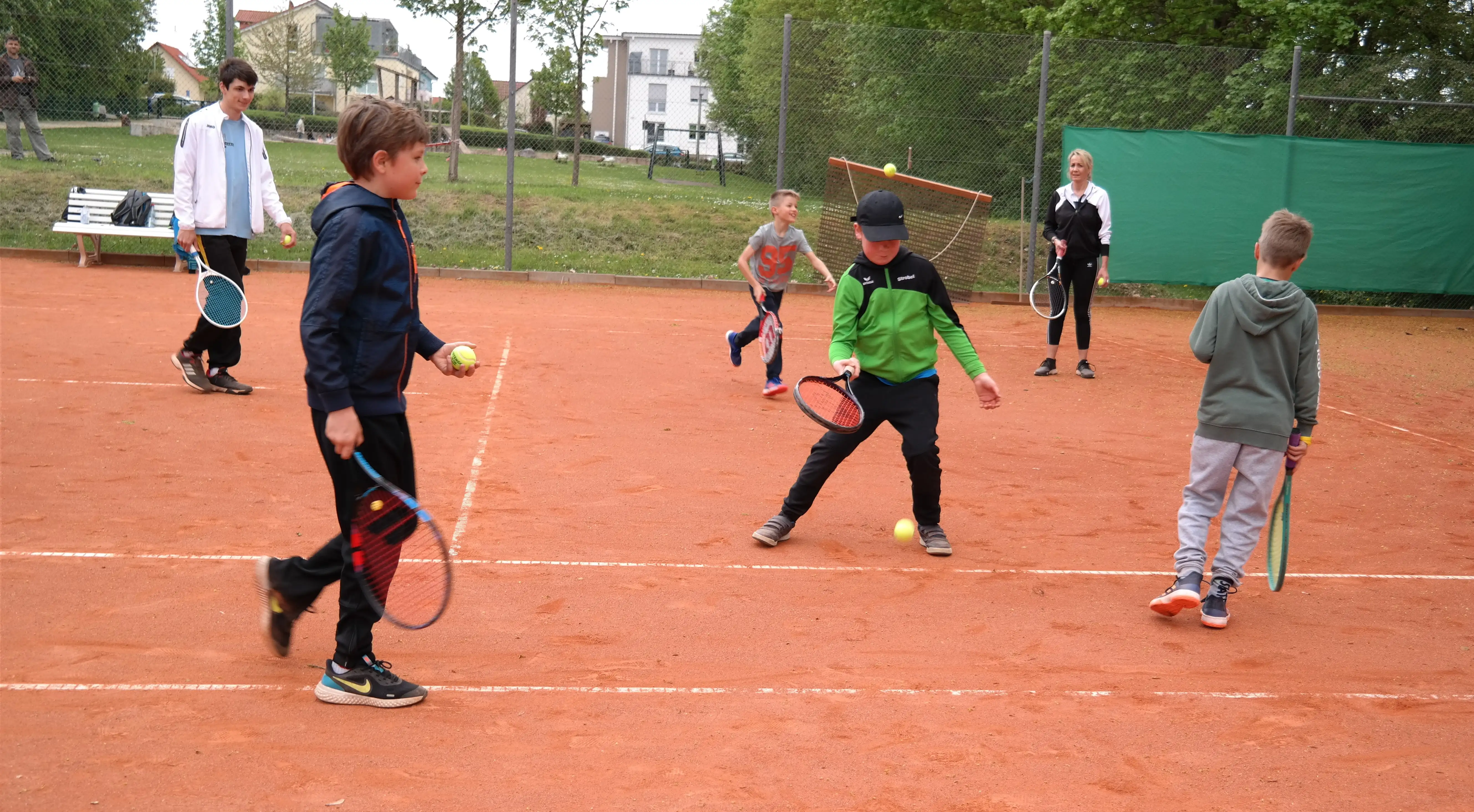 Trainer üben mit Kindern Tennisspielen